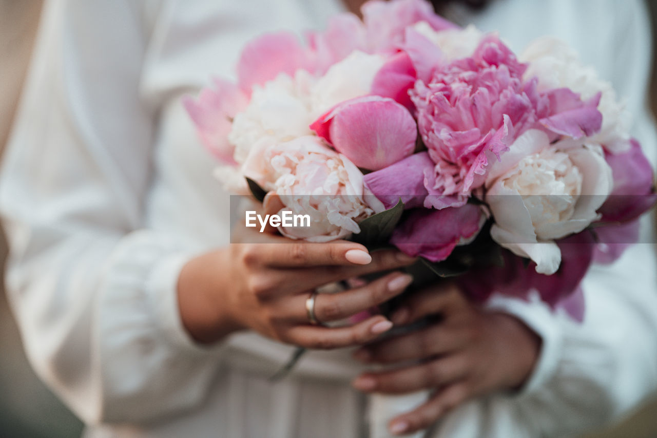 Midsection of woman holding pink rose bouquet