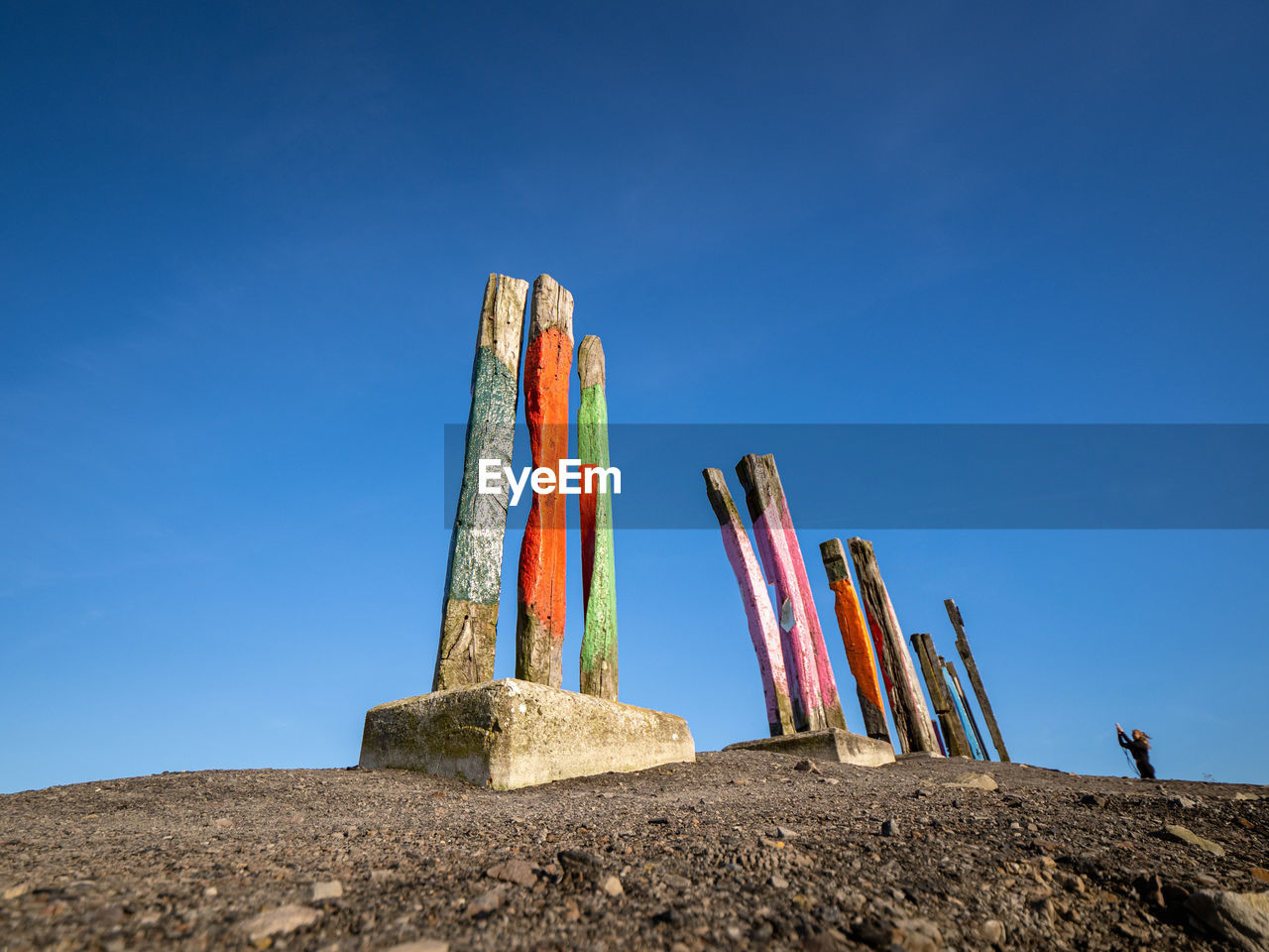 low angle view of man standing on rock against clear blue sky
