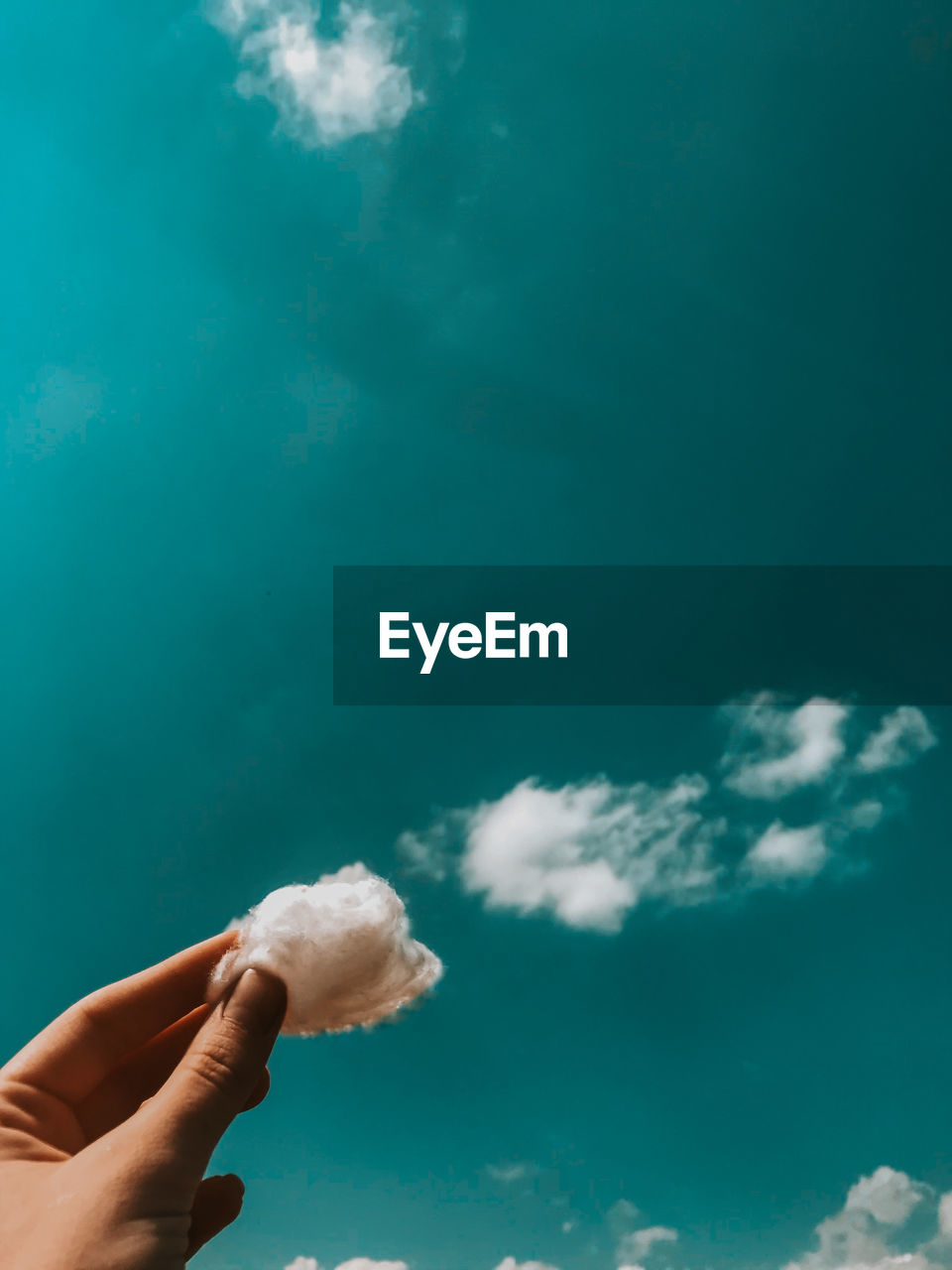 Person holding cotton against sky