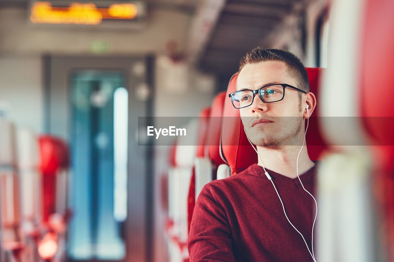 Young man listening to music while traveling in train