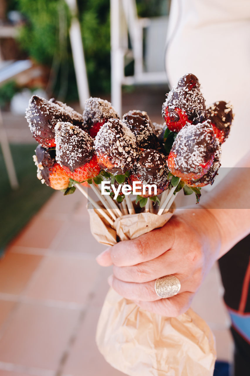 A bouquet of chocolate covered strawberries with different toppings chocolate coconut cocoa 