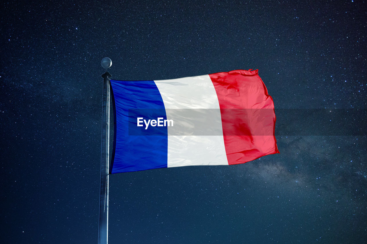 Low angle view of french flag against star field sky