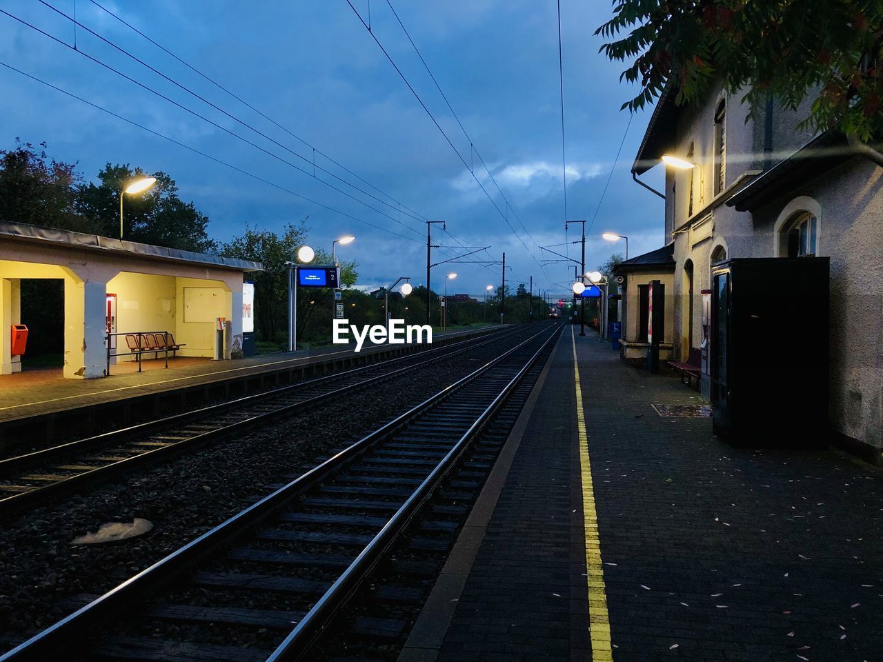 RAILROAD TRACKS AMIDST BUILDINGS AGAINST SKY AT STATION