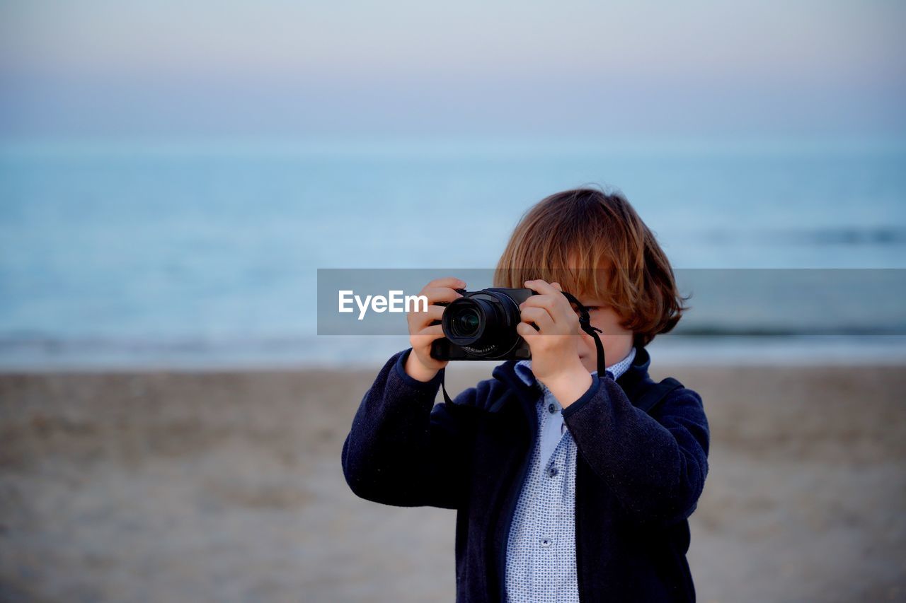 Boy photographing from camera at beach