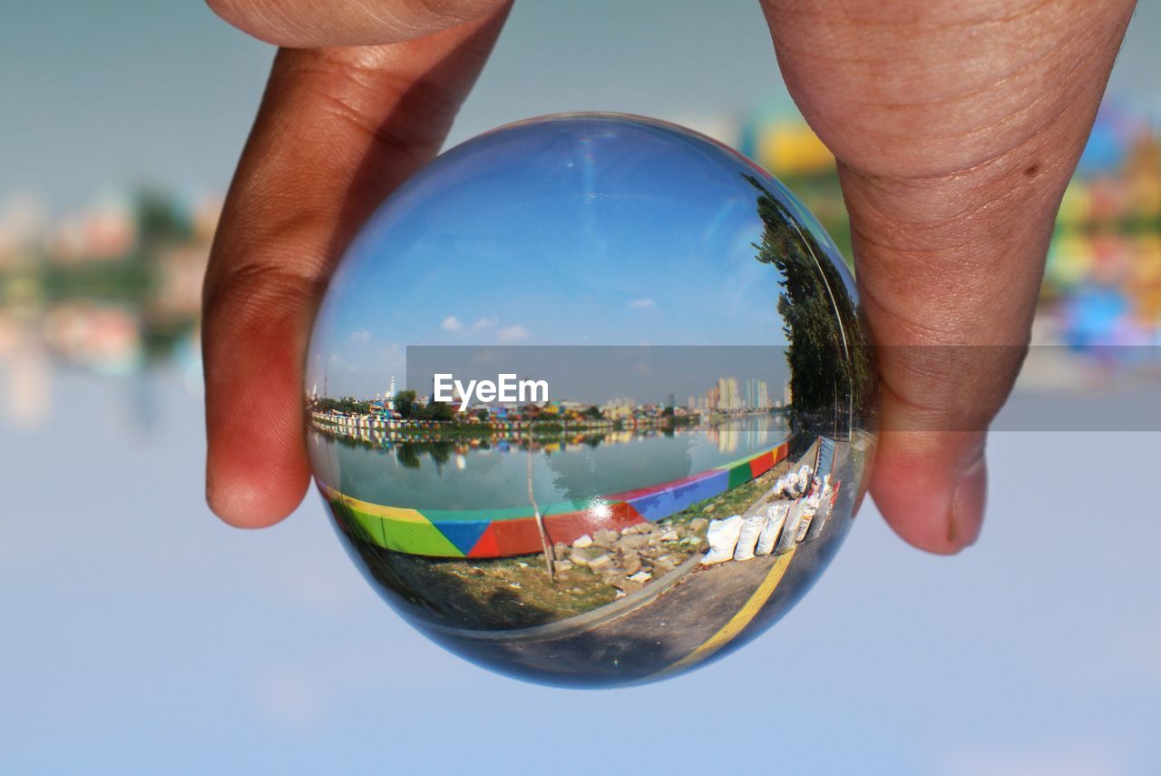 sphere, hand, holding, sky, nature, globe - man made object, one person, reflection, planet earth, crystal ball, close-up, water, transparent, adult, blue, outdoors, business, glass, travel, day, city, architecture, space, planet, men, building exterior, focus on foreground, global business, travel destinations, sea, environment