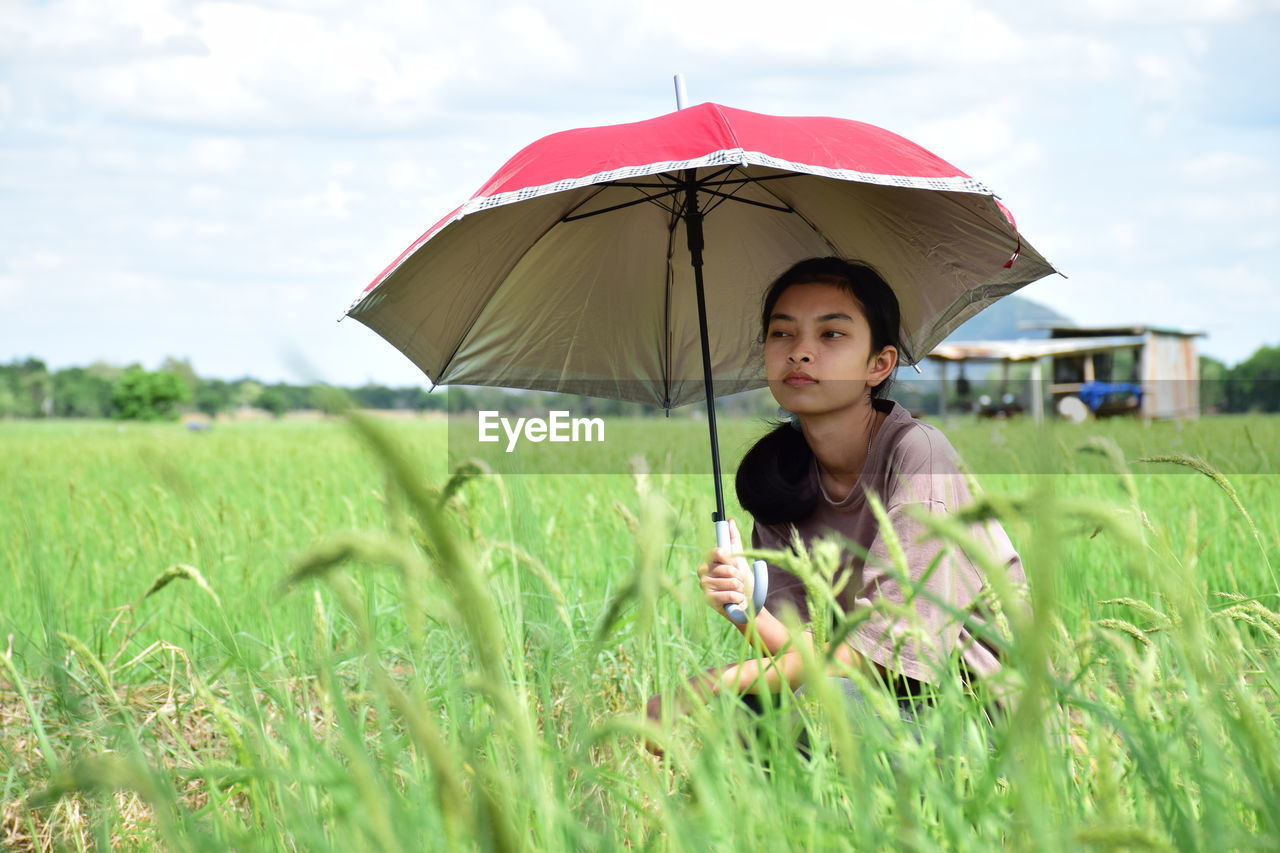 Woman holding umbrella on field