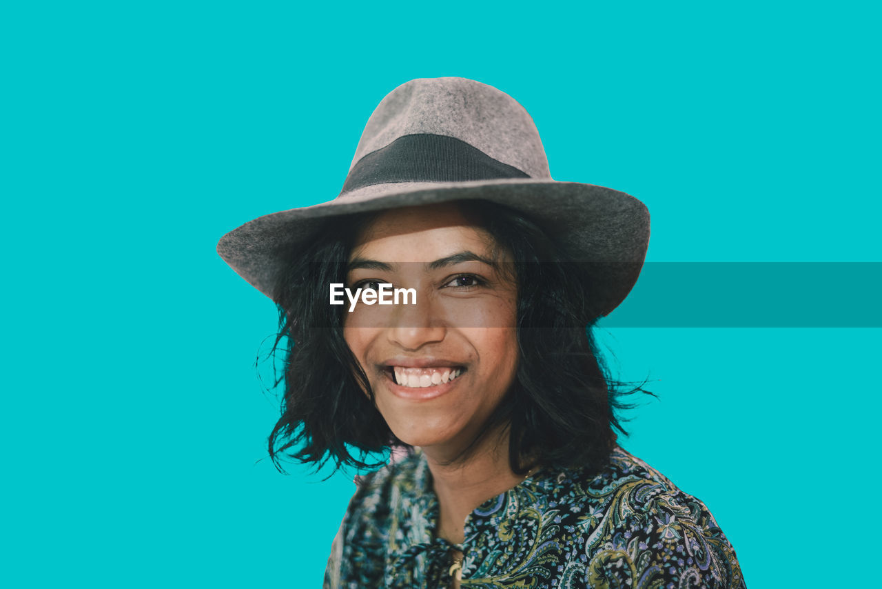 portrait of woman wearing hat against blue background