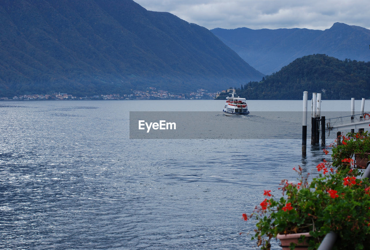 Boat sailing on sea by mountains against sky