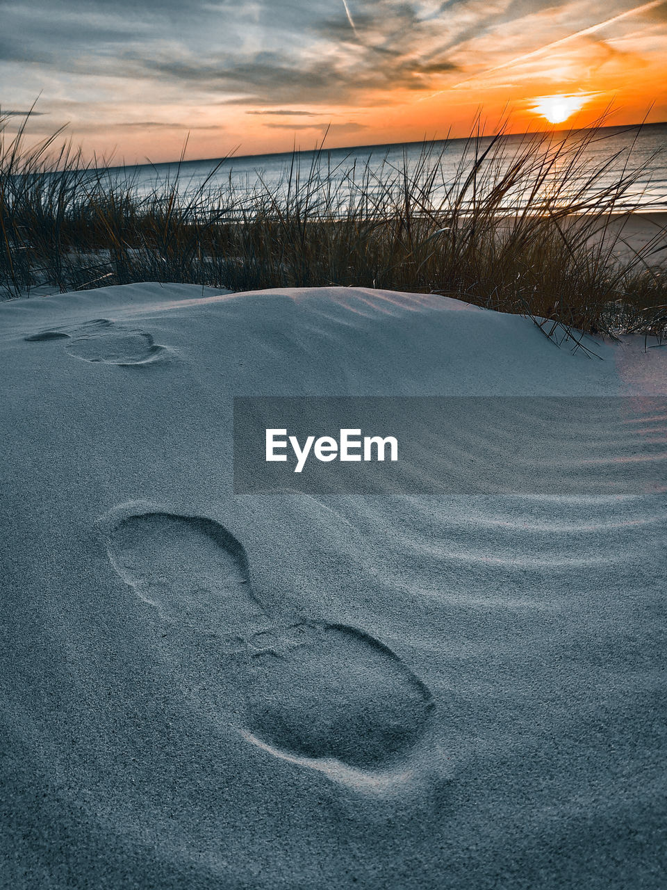 Snow covered land against sky during sunset