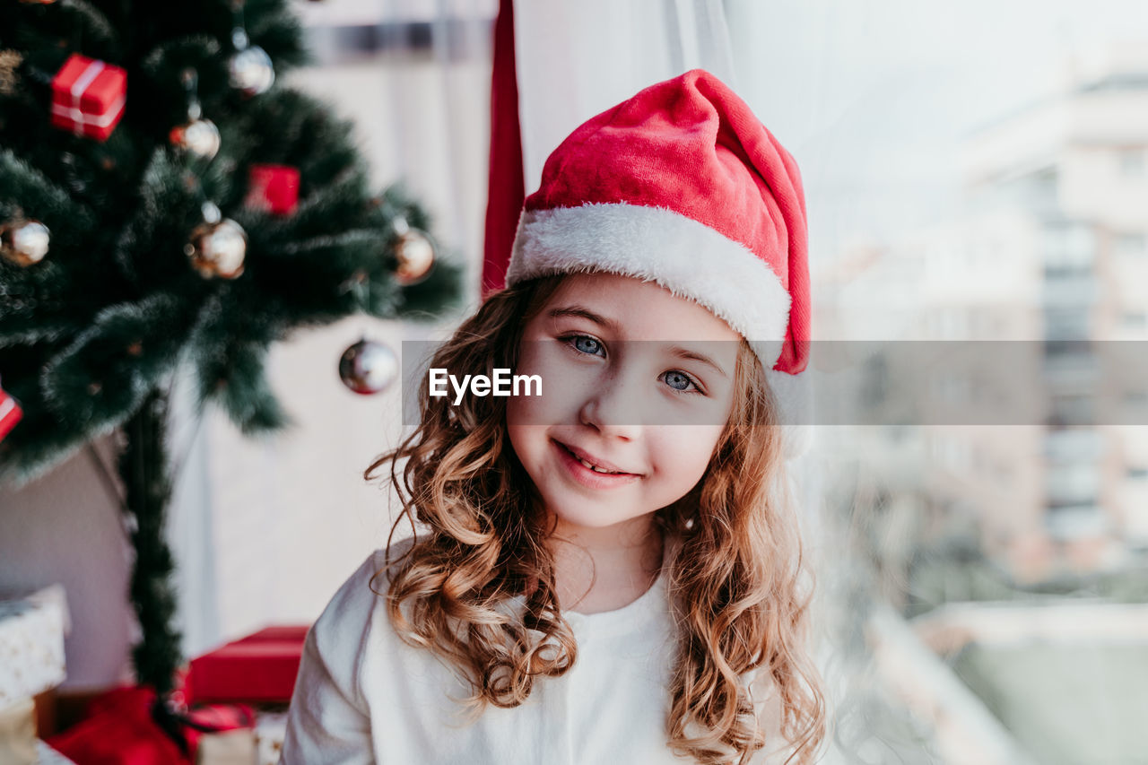 Portrait of happy girl with hat on christmas tree