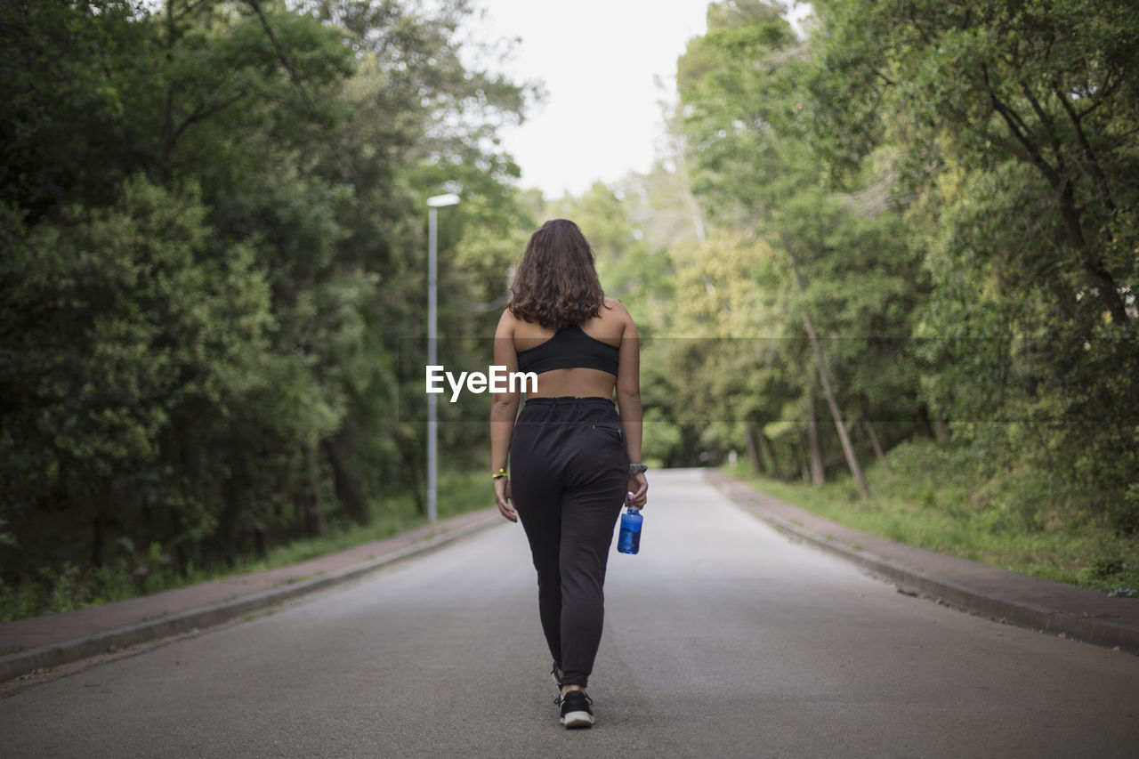 Rear view of woman on road amidst trees