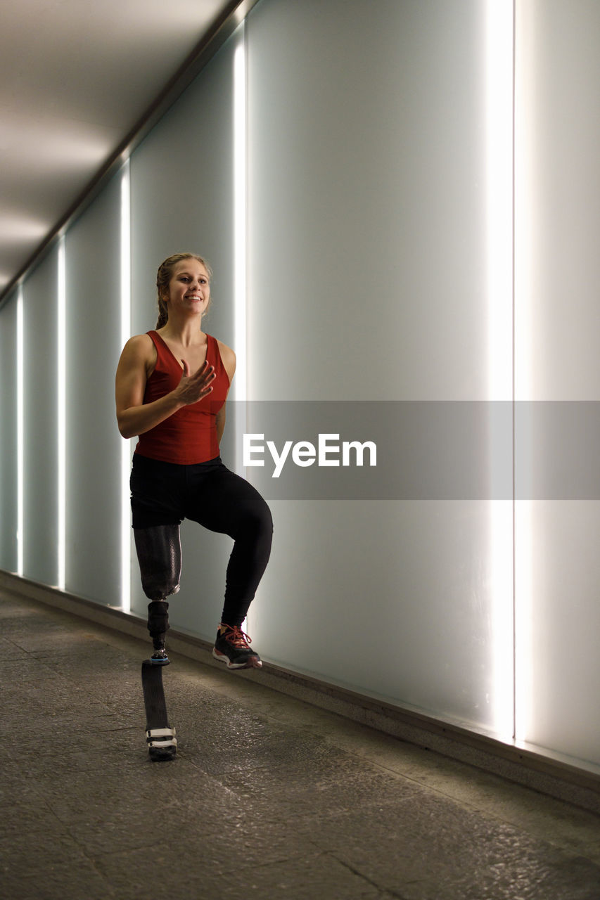 Young athlete with artificial leg running while exercising in underpass