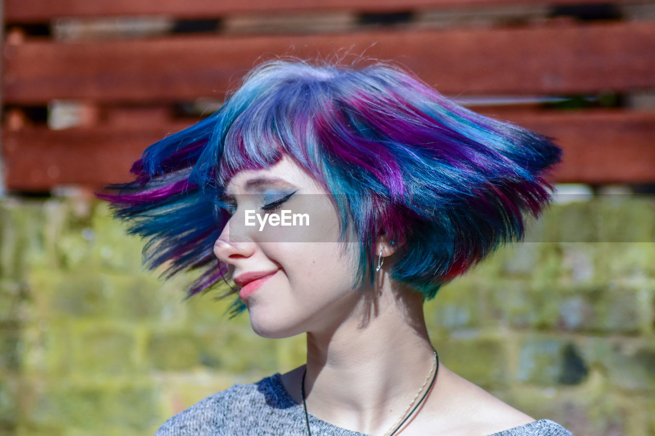 Hipster woman tossing colorful dyed hair outdoors
