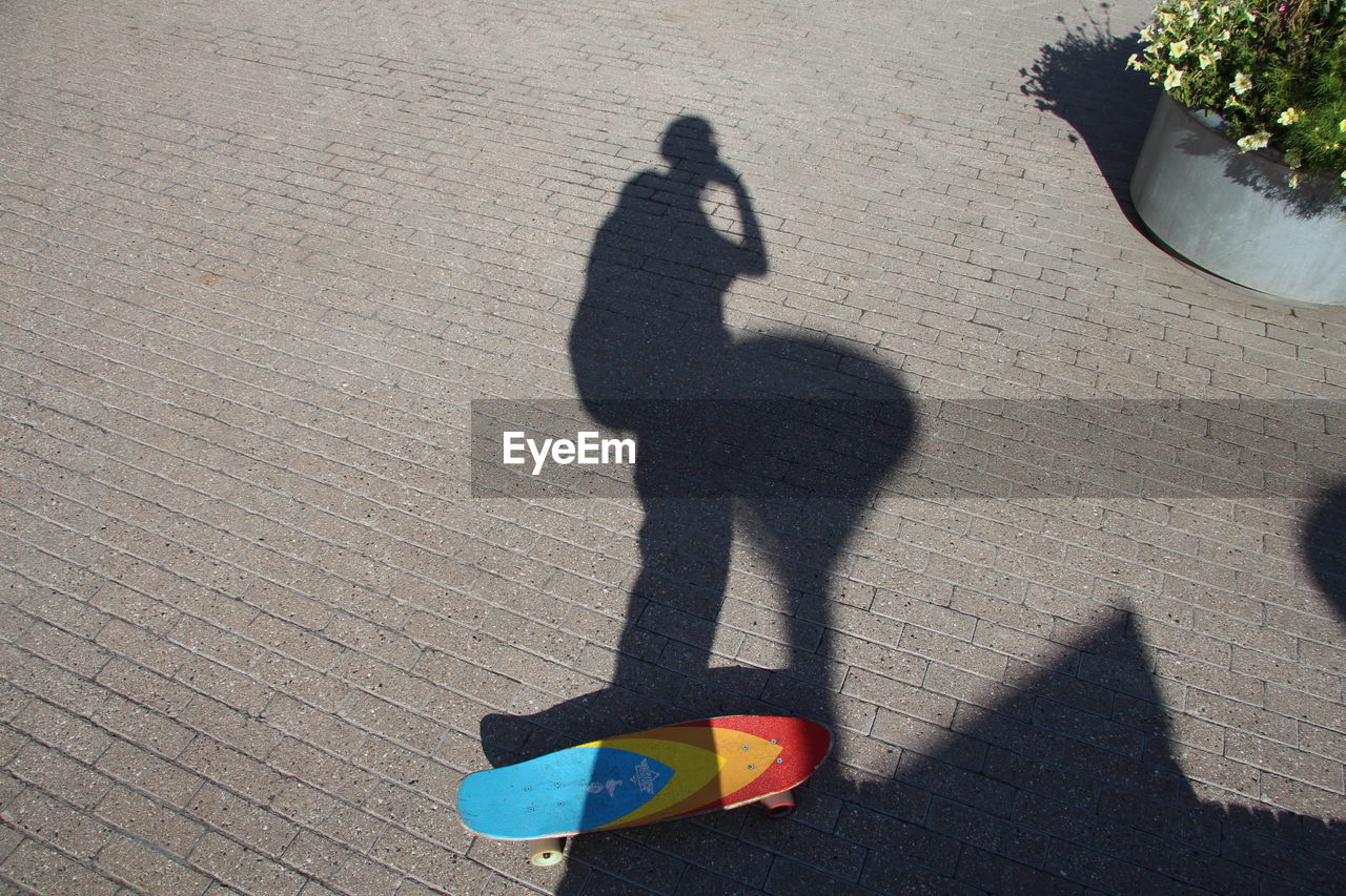 Shadow of people on skateboard over footpath