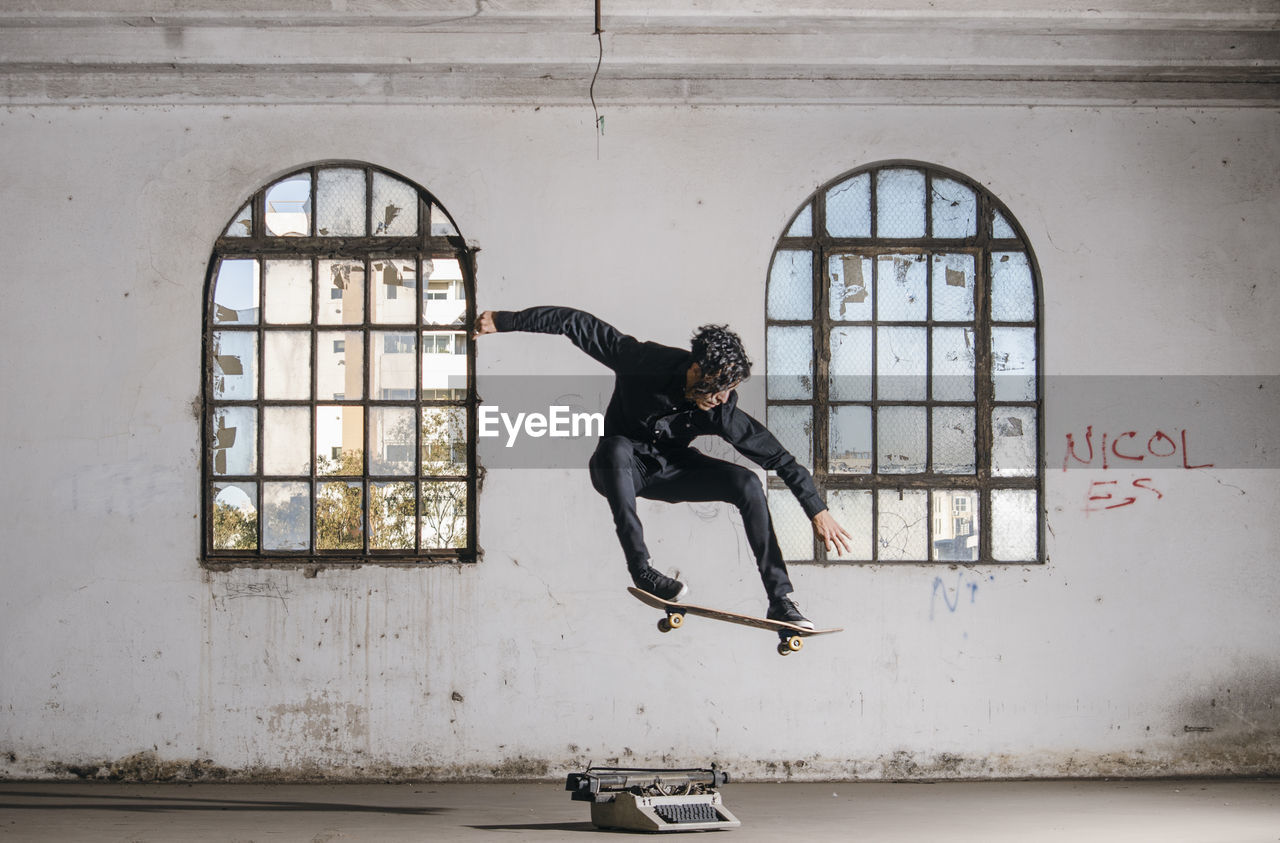 Full length of man skateboarding against windows