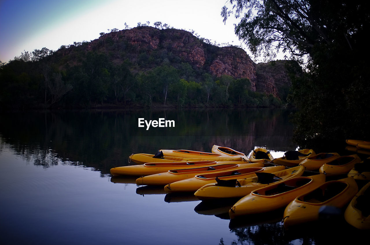 Yellow kayaks on river with reflection against mountain