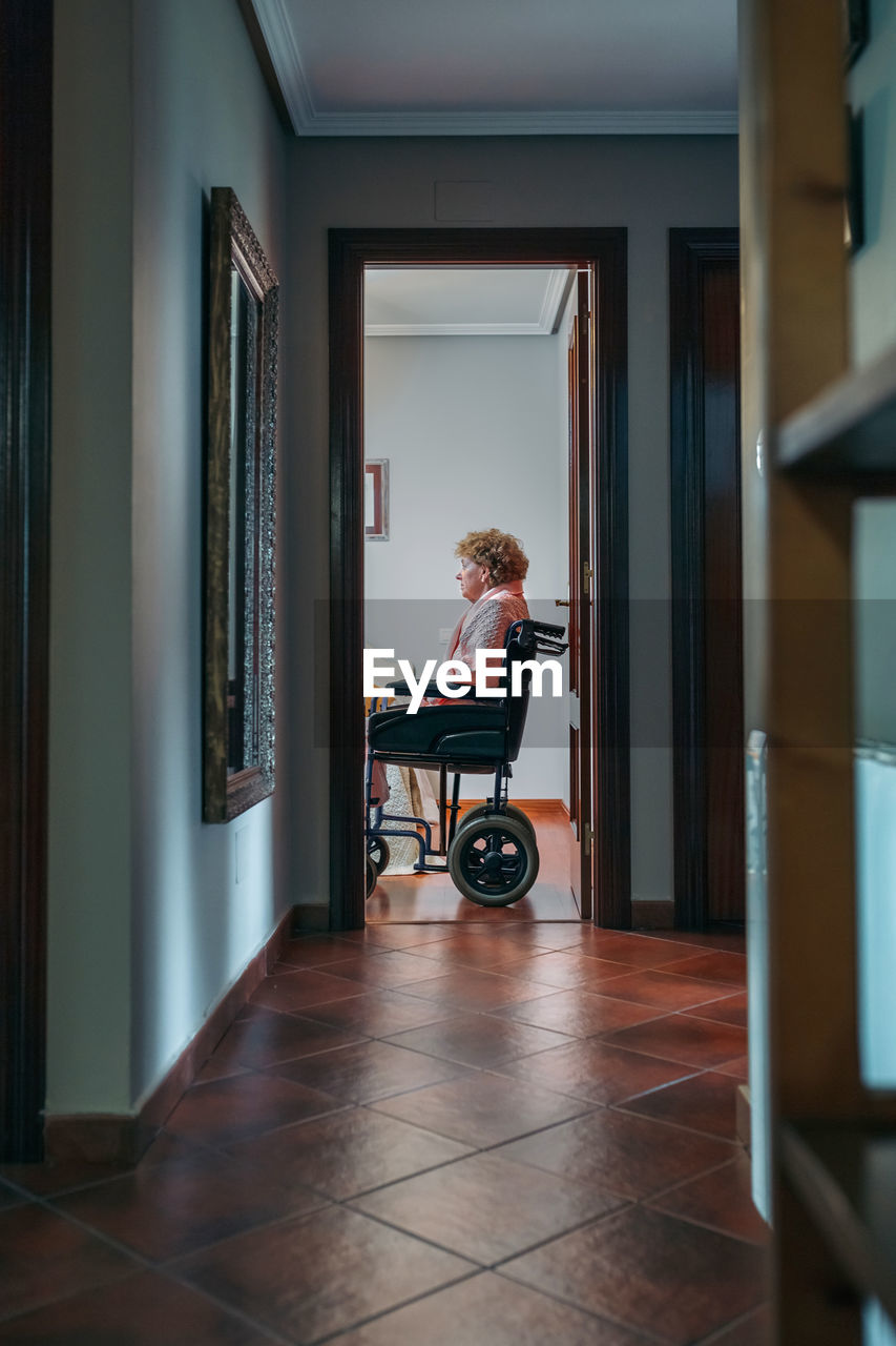 Woman sitting on wheelchair at home