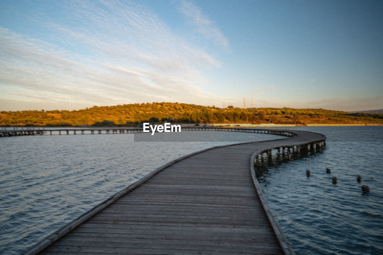 horizon, sky, reflection, morning, shore, water, dusk, sea, nature, scenics - nature, beauty in nature, sunrise, sunlight, tranquility, no people, tranquil scene, coast, cloud, landscape, environment, ocean, land, wave, wood, outdoors, the way forward, blue, pier, body of water, non-urban scene, reservoir, footpath, day, boardwalk, beach, travel destinations, architecture, travel, idyllic