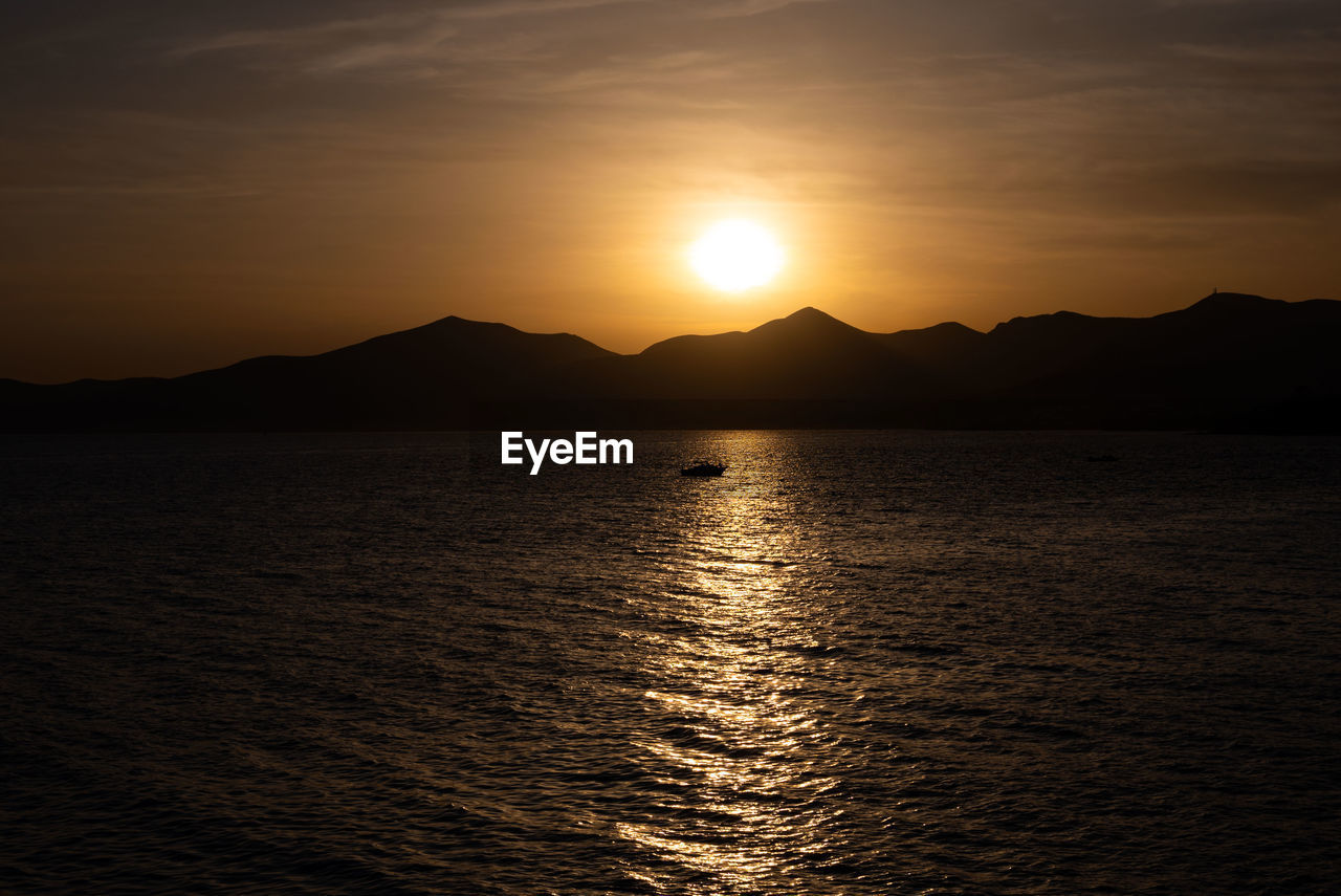 water, sky, mountain, beauty in nature, scenics - nature, sea, sunset, tranquility, horizon, tranquil scene, nature, sunlight, reflection, mountain range, sun, no people, idyllic, ocean, silhouette, afterglow, cloud, land, coast, environment, dramatic sky, travel destinations, outdoors, dawn, travel, landscape, non-urban scene, seascape, evening, rippled, orange color, beach