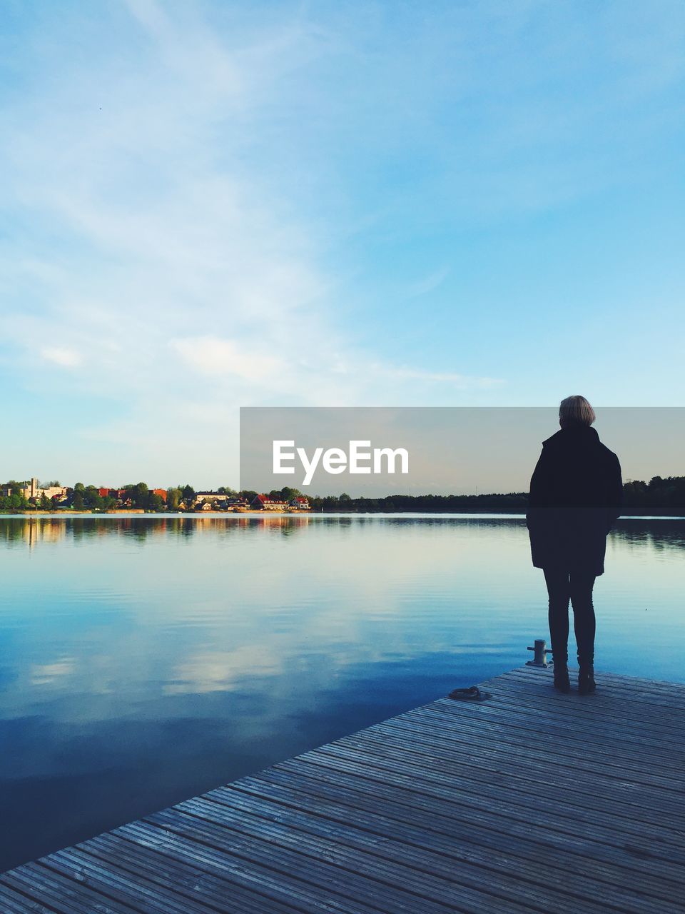 REAR VIEW OF A WOMAN OVERLOOKING CALM SEA