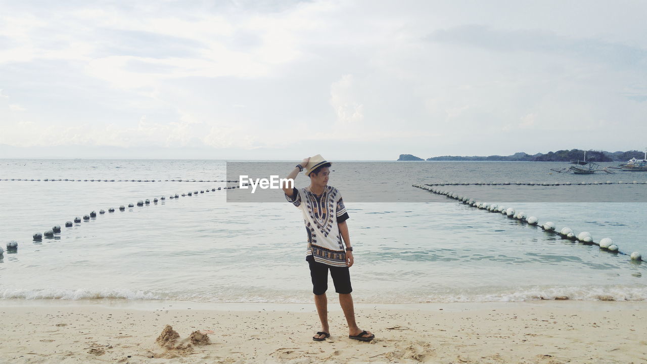 Full length of young man standing at beach