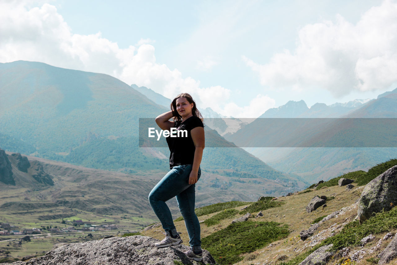 Portrait of woman standing on rock against mountain range