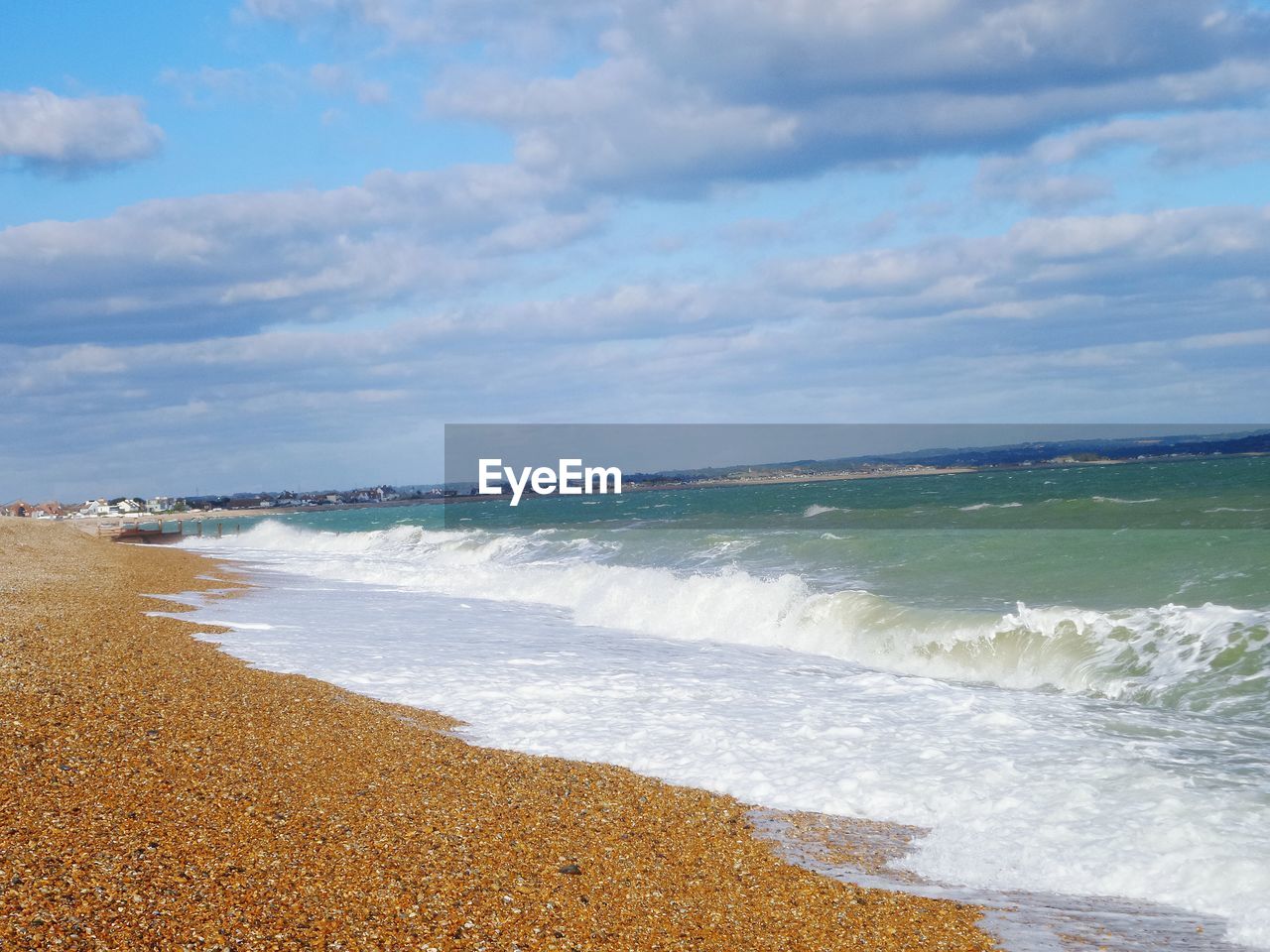 View of calm beach against cloudy sky