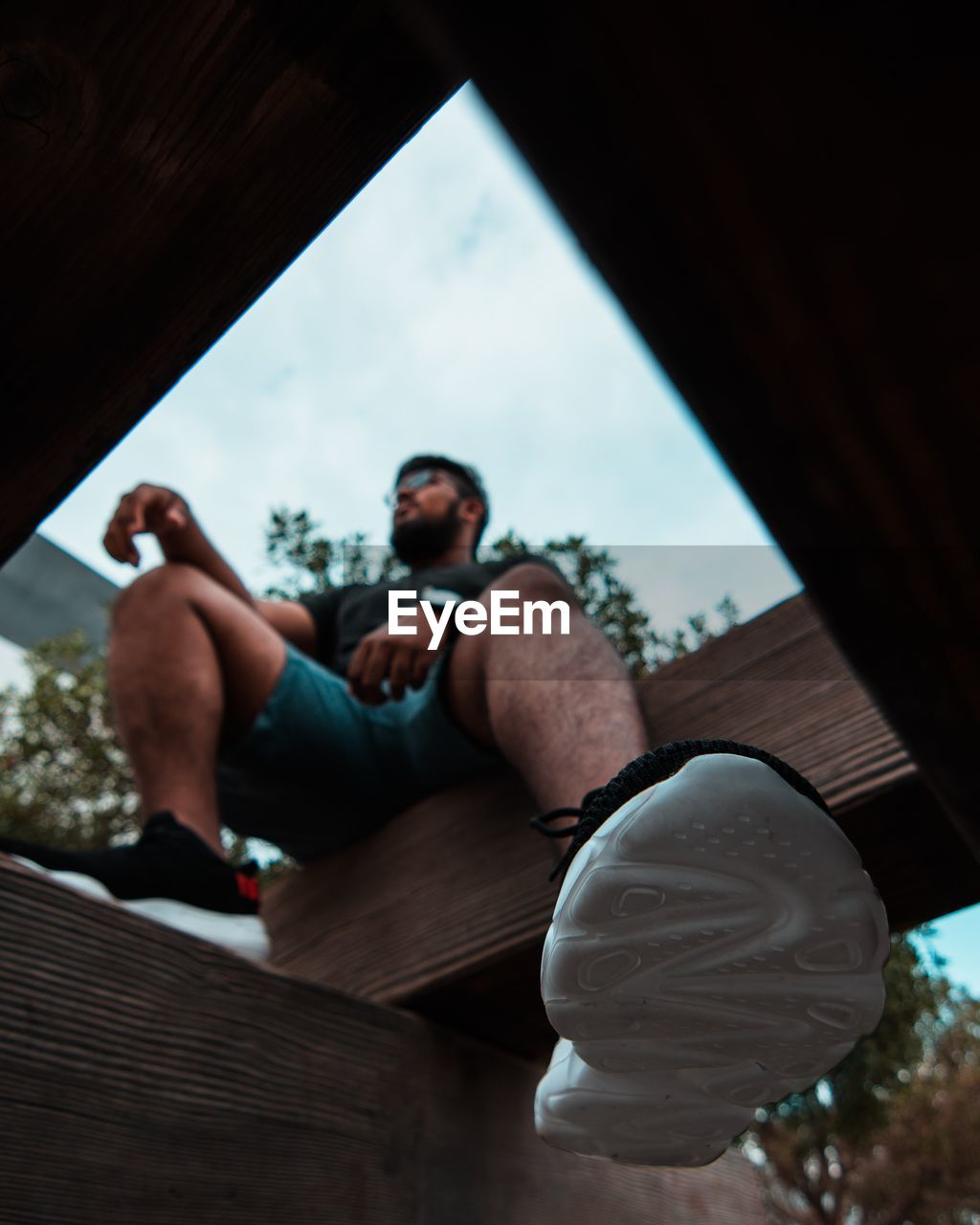 LOW ANGLE VIEW OF MAN SITTING BY WINDOW