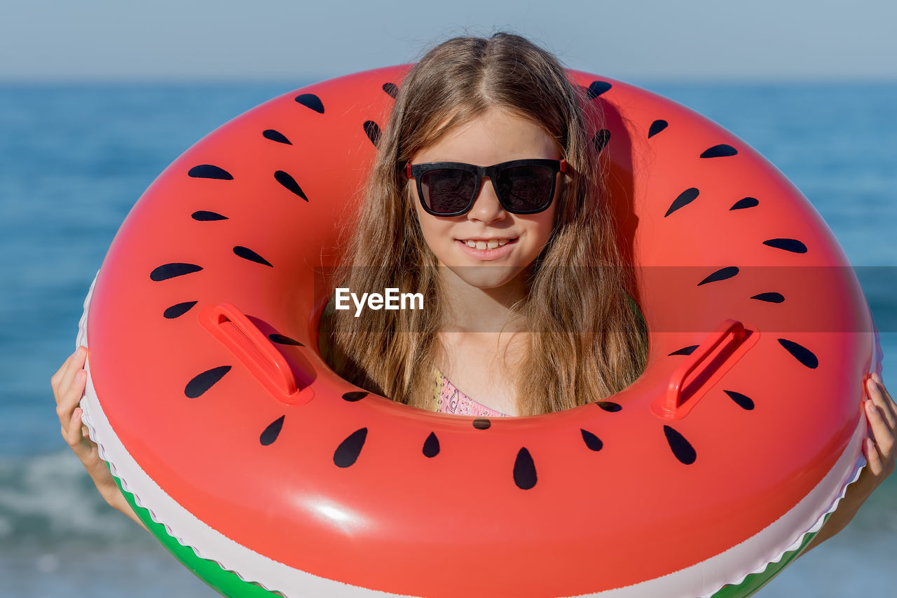 A girl in a swimsuit with an inflatable ring - a watermelon on the background of the sea. 