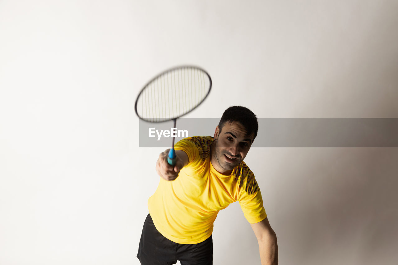 YOUNG MAN STANDING AGAINST YELLOW BACKGROUND