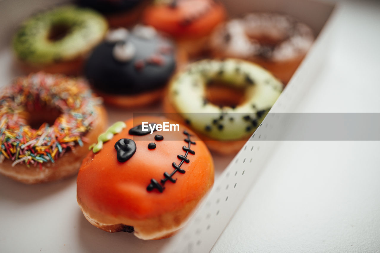 Assortment of halloween monsters with funny faces donuts in box at home interior