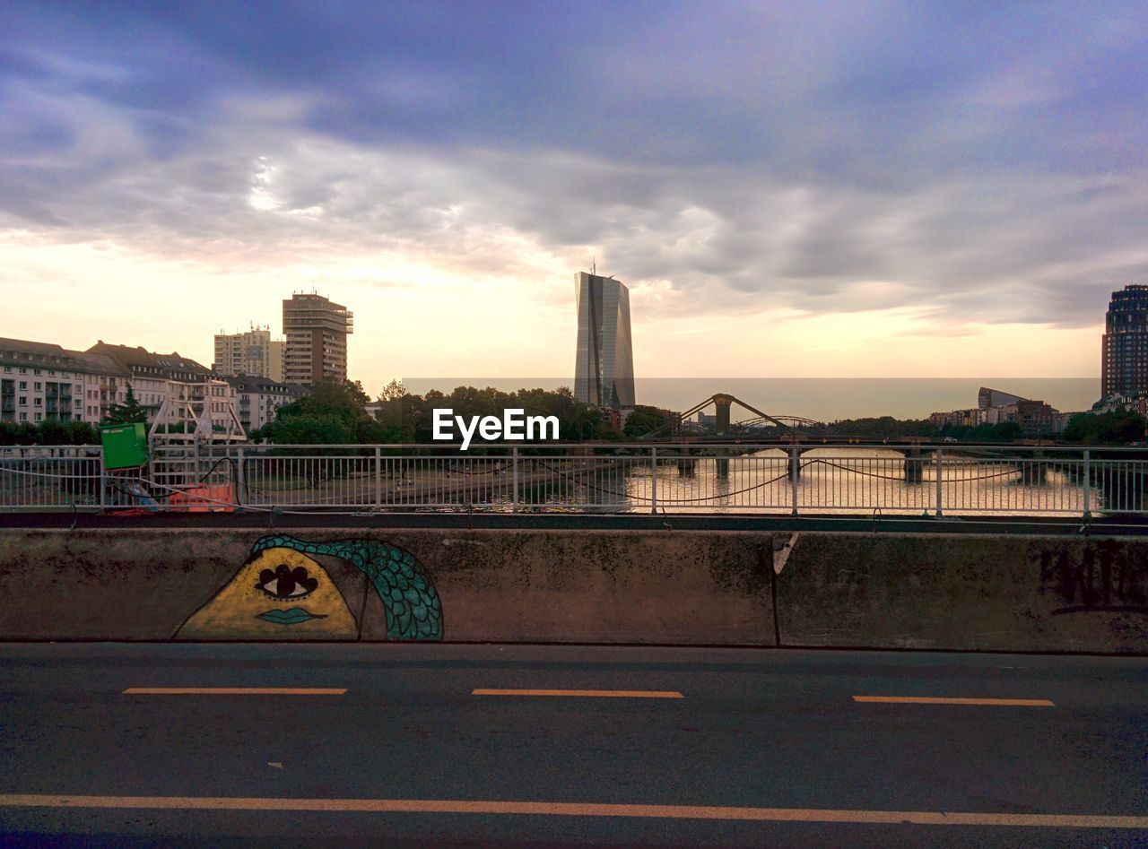 VIEW OF CITYSCAPE AGAINST CLOUDY SKY AT SUNSET