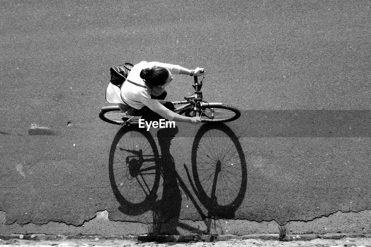 Woman riding bicycle on street, from above 