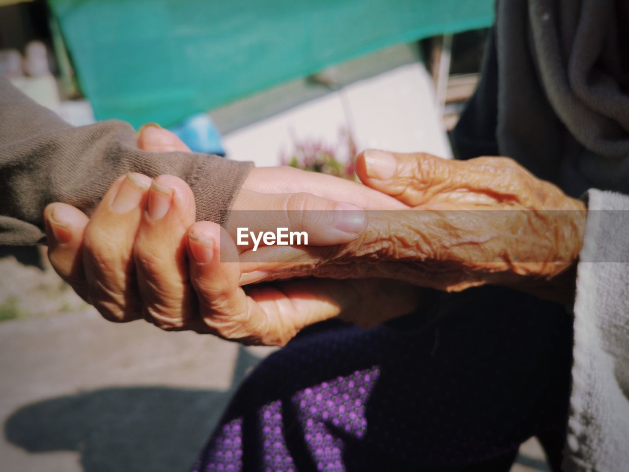 Midsection of senior woman holding grandchild hand outdoors