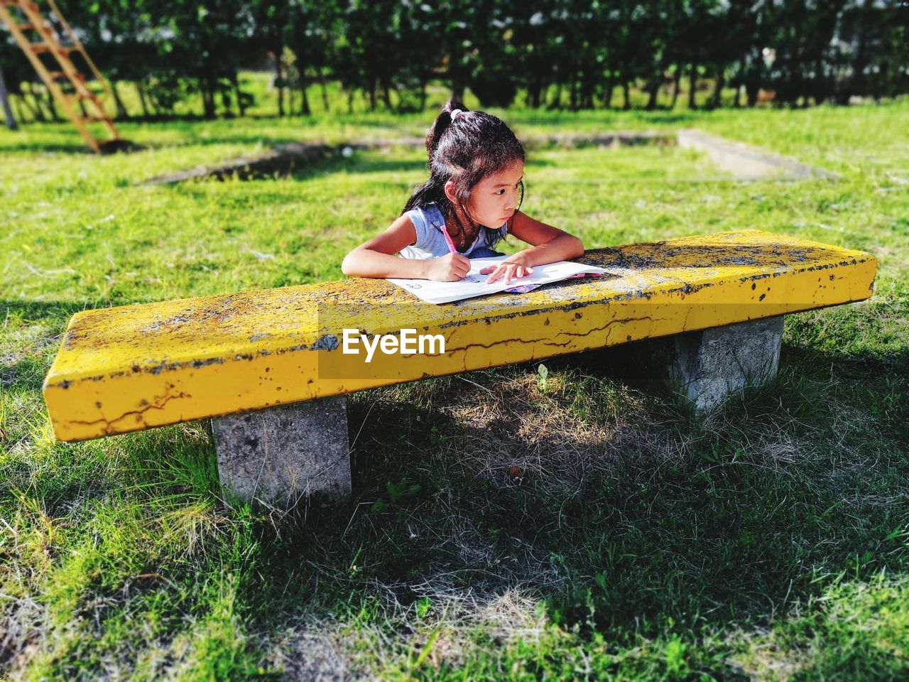 Girl writing in book at bench