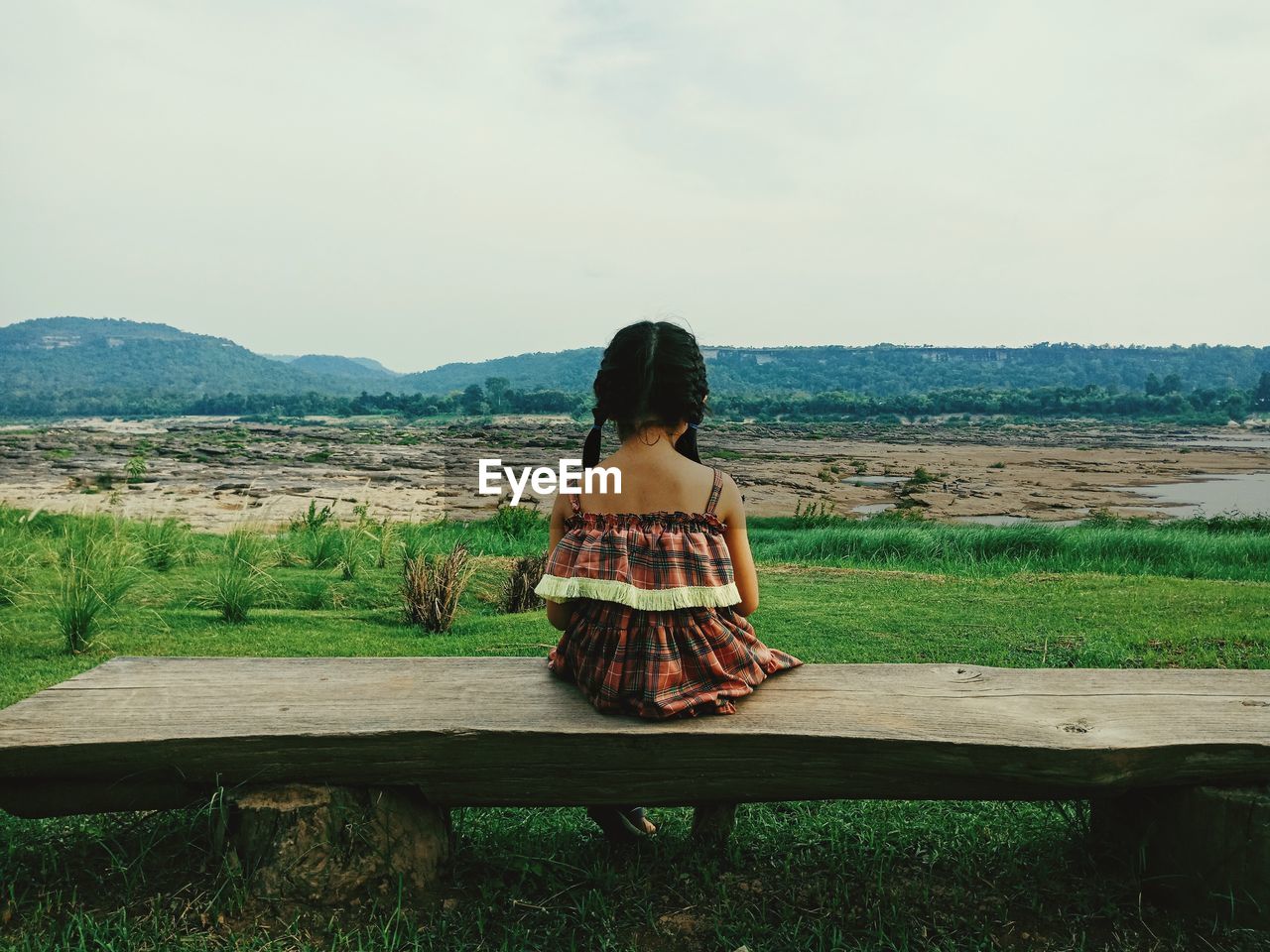 YOUNG WOMAN SITTING ON BENCH IN PARK