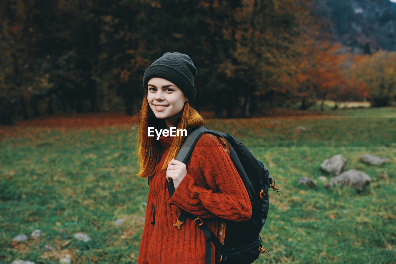 PORTRAIT OF SMILING WOMAN STANDING ON FIELD DURING AUTUMN