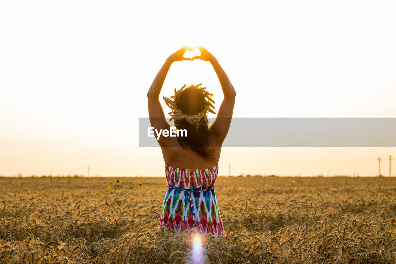 Young woman standing on field against clear sky