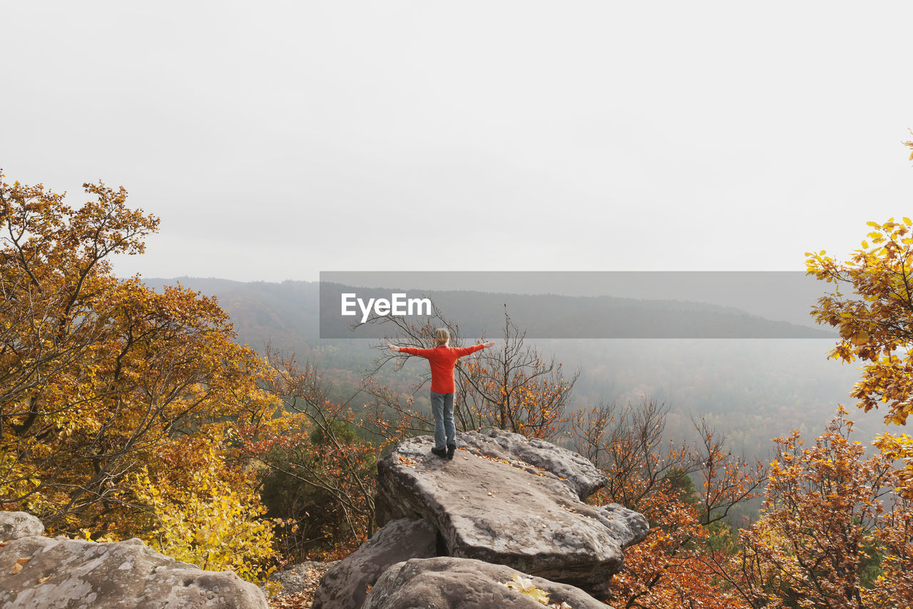 Germany, rhineland palatinate, palatinate forest, woman practising yoga on drachenfels in autumn