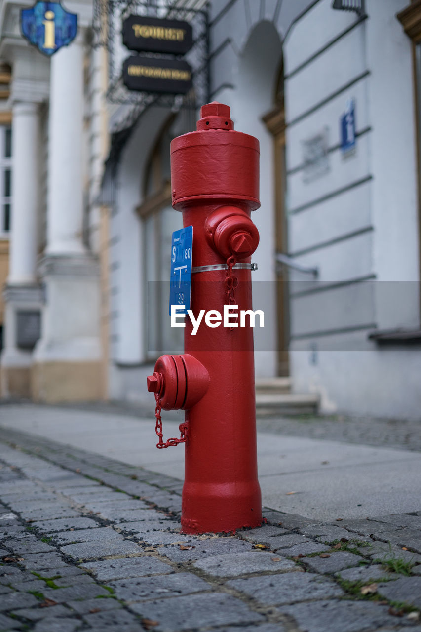 Red fire hydrant on footpath by building