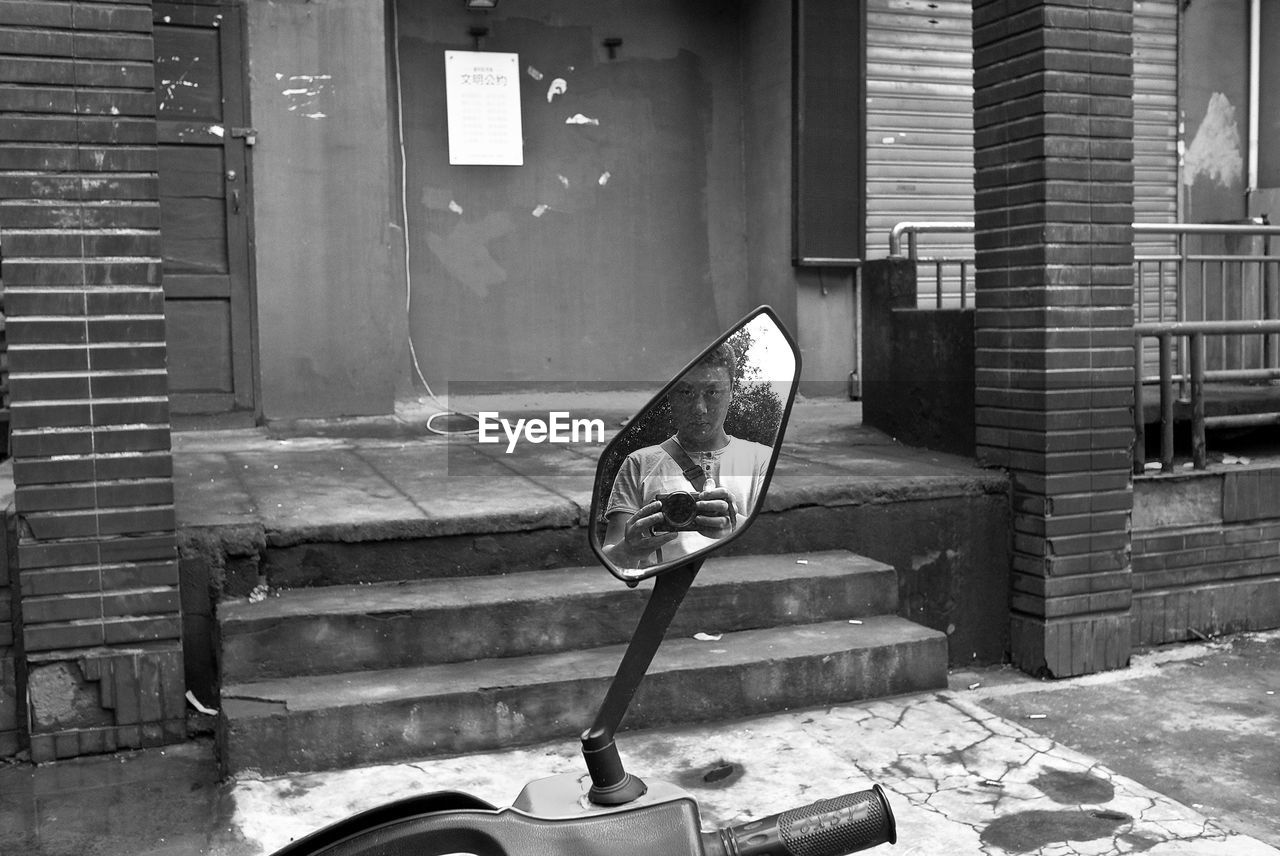 Reflection of man photographing seen in mirror