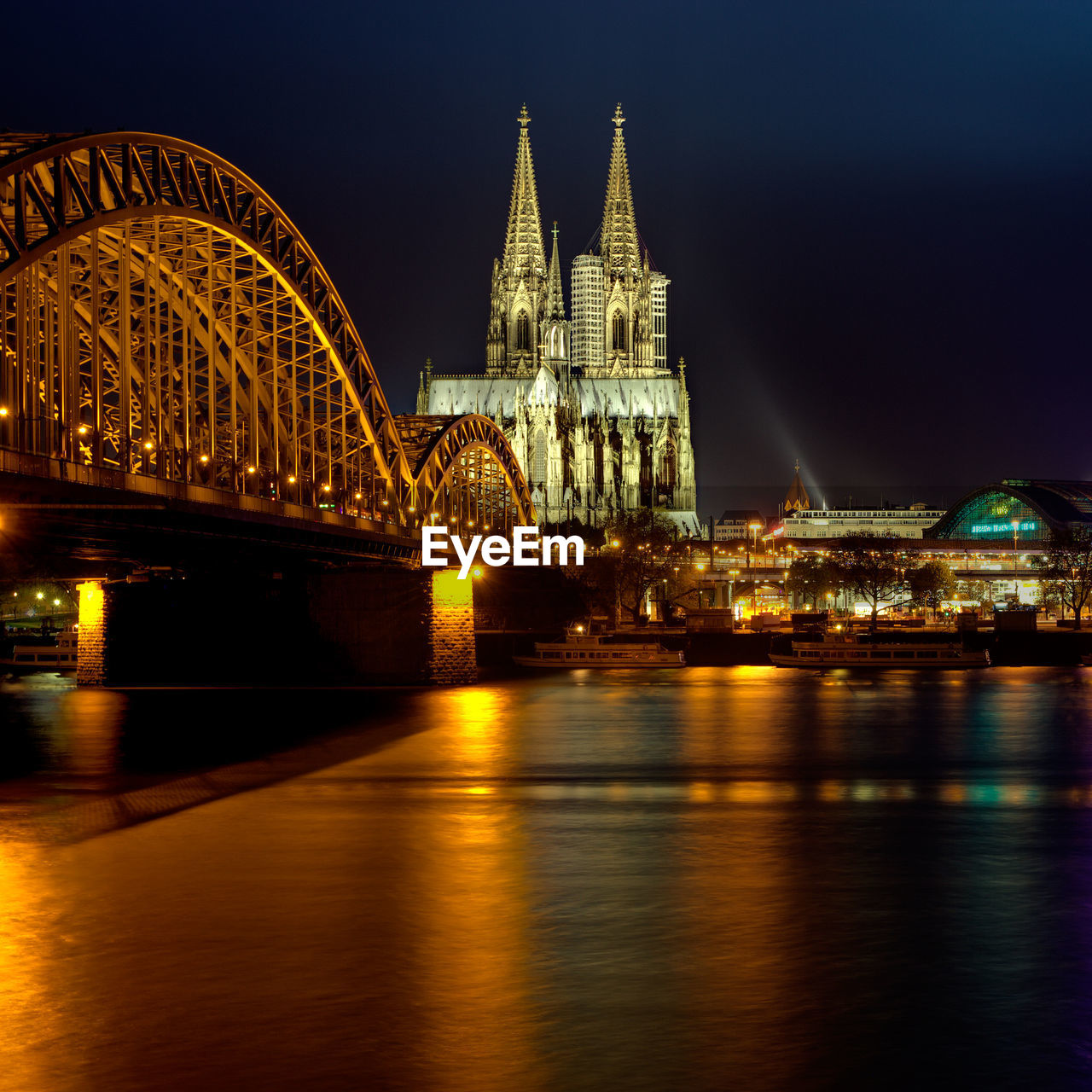 Illuminated hohenzollern bridge against cologne cathedral and buildings at night