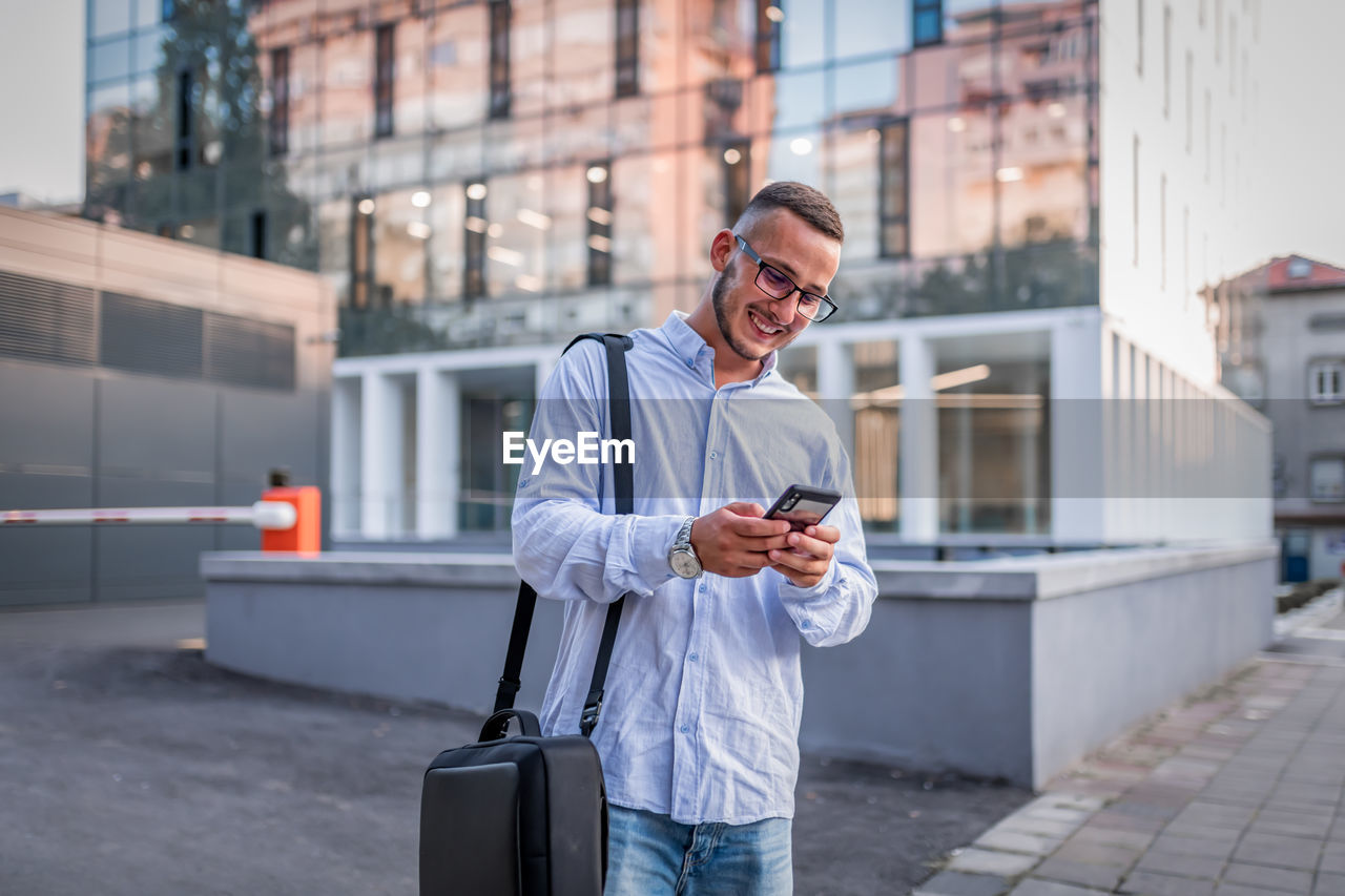 Portrait of young handsome businessman with eyeglasses and shirt walking in the street