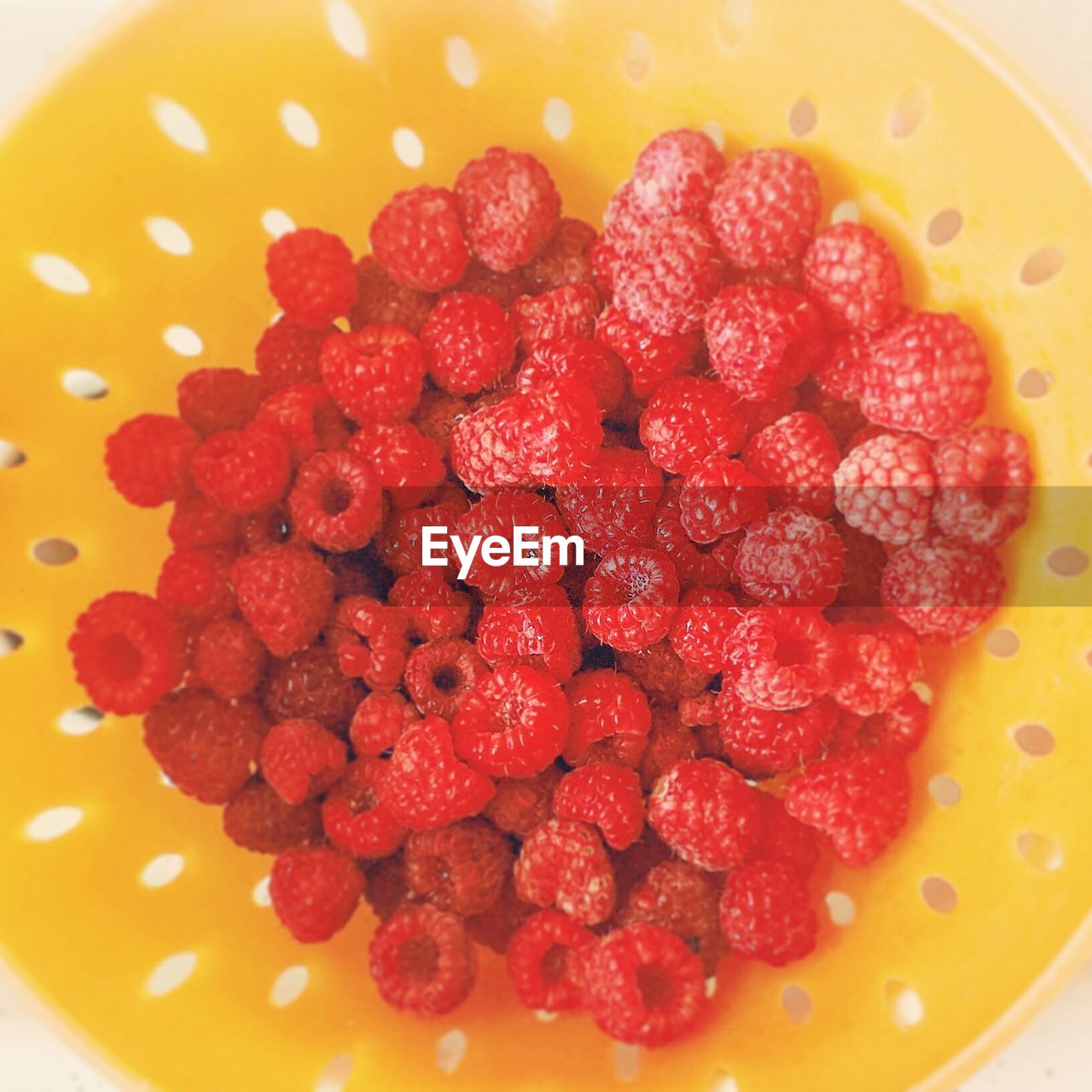 Directly above shot of raspberries in yellow bowl