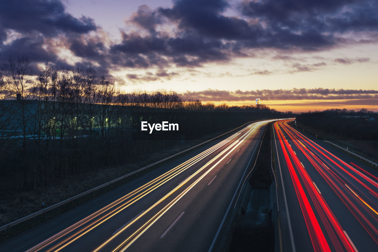 Light trails on road against sky at sunset