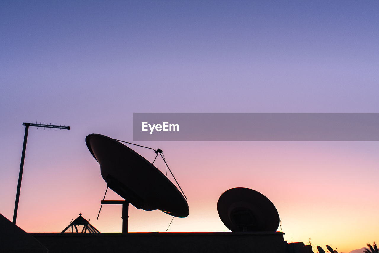Low angle view of silhouette dish antenna against sky during sunset