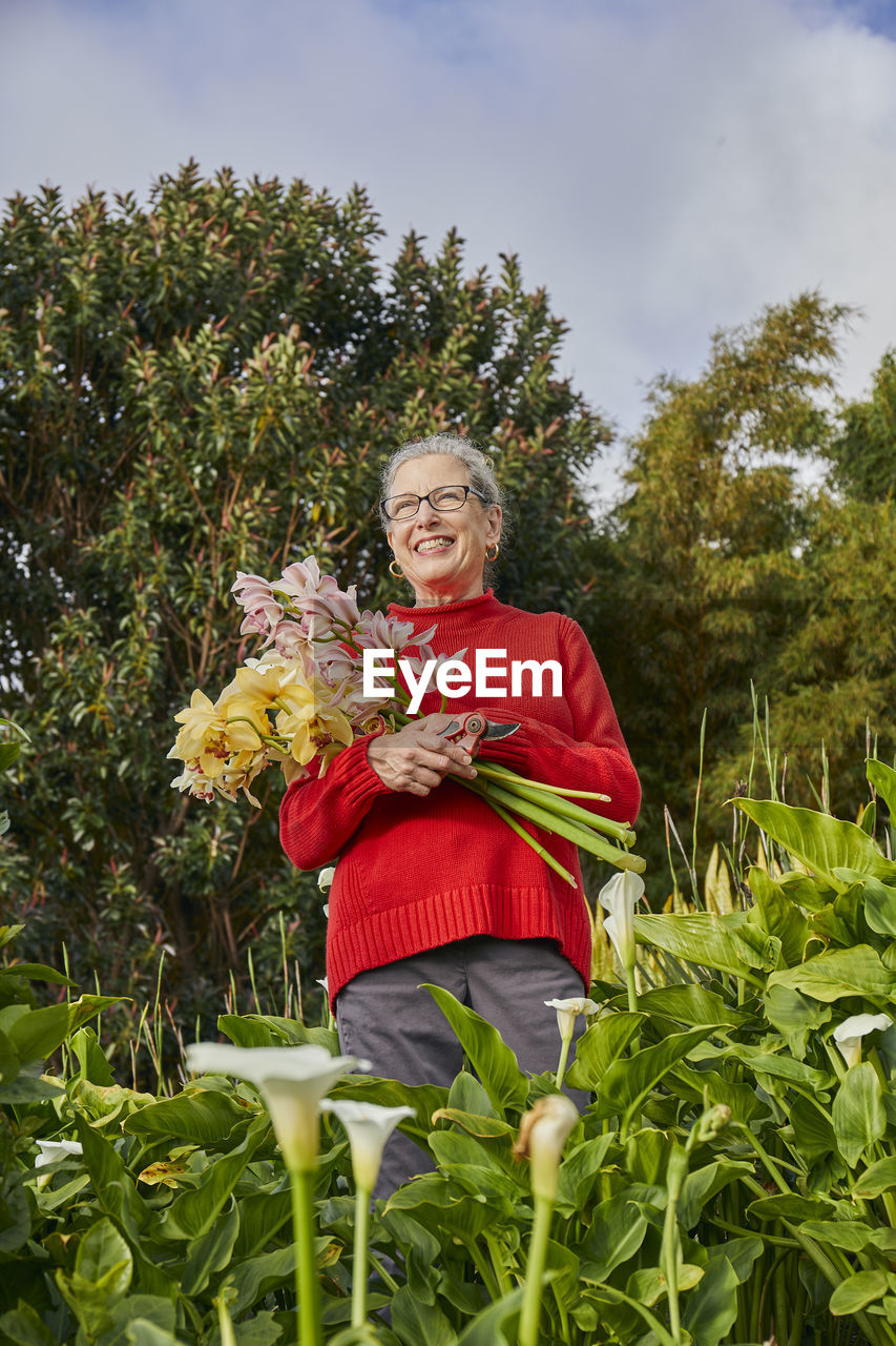 Retired woman holding freshcut flowers in her garden
