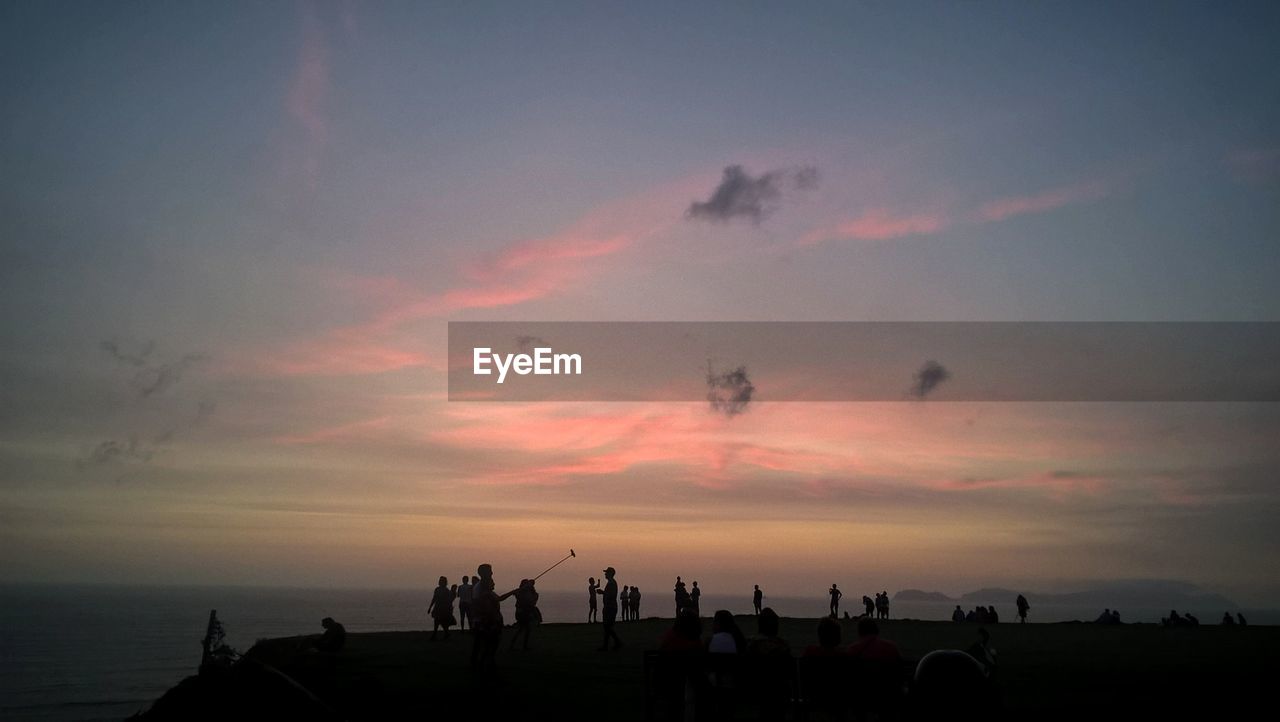 People standing against sea during sunset