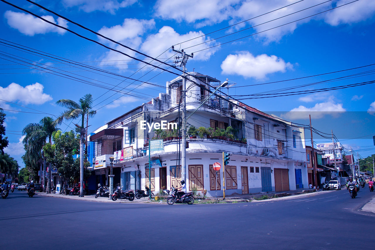 Street by buildings in city against sky