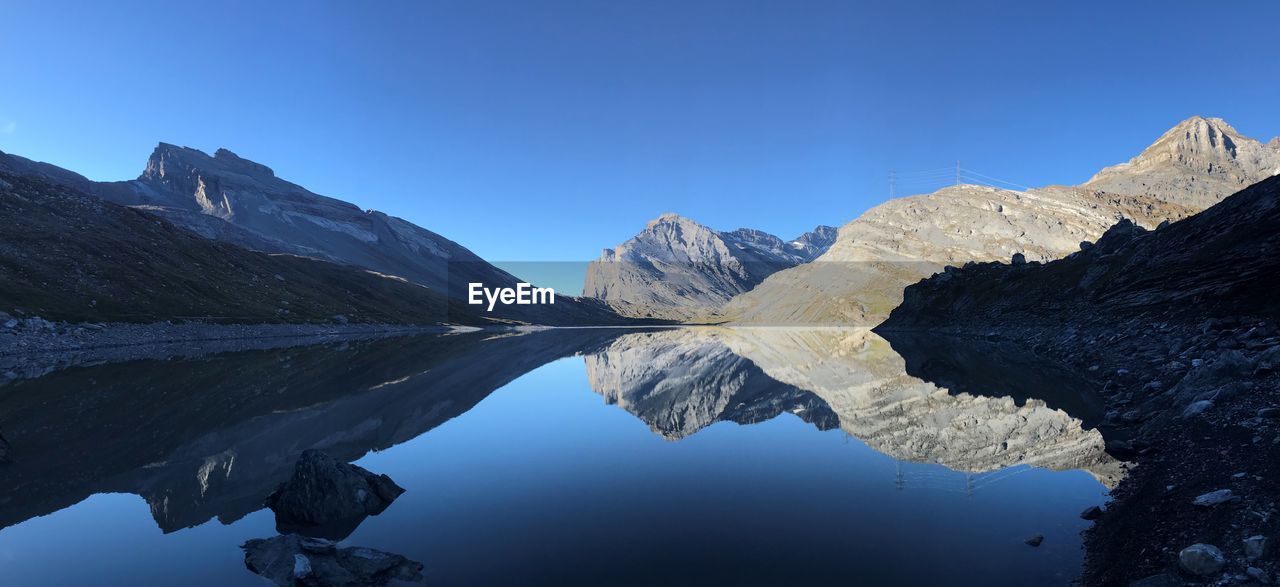 Scenic view of lake and mountains against clear blue sky